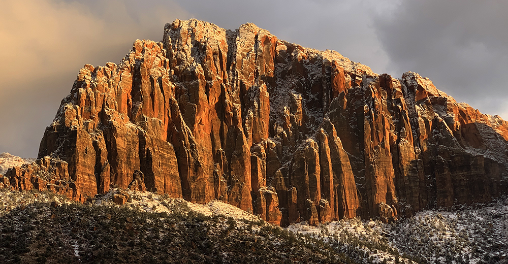 light amounts of snow grace the glow of sunset against the red cliffs of the Watchman.