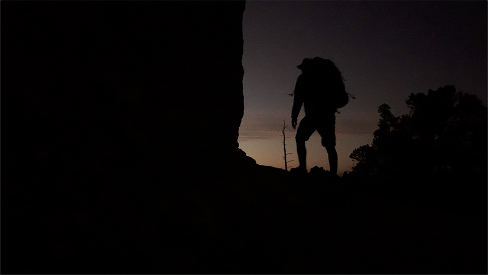 A hiker stands silhouetted against the early sunrise on a Bryce Canyon trail. 