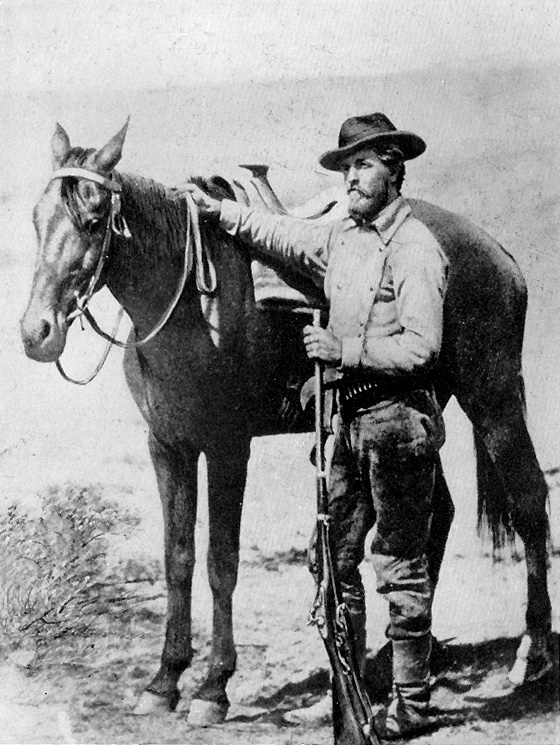 early yellowstone photographer william jackson posing with a rifle beside a horse
