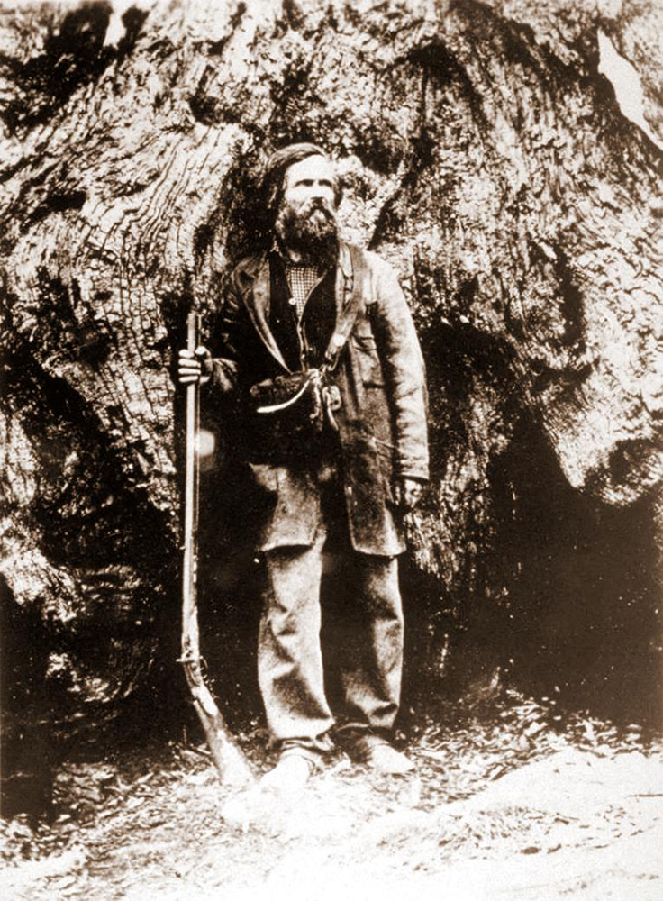 galen clark stand in front of big tree with rifle